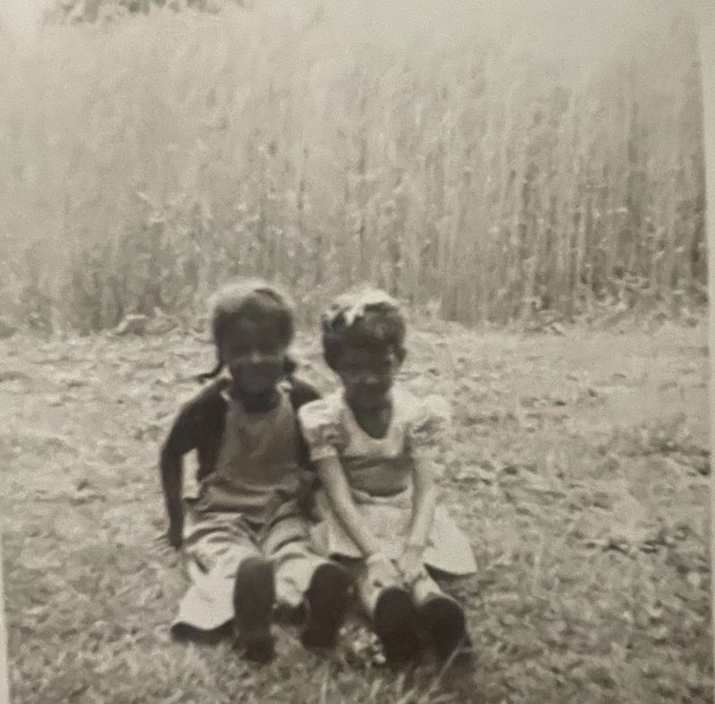 Vintage family photo of two children sitting in front of a wheat field