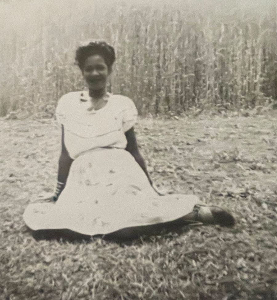 Vintage photo from Wesley's family album: a young woman sitting in front of a wheat field